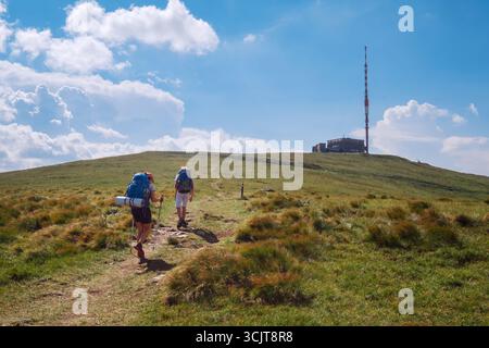 Madre con figlio trekkers con backback utilizzando pali di tracciamento che camminano fino alla montagna Kralova Hola 1946m con trasmettitore TV della slovacca Low Fatras corse Foto Stock