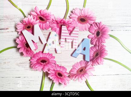La parola tedesca mamma, mamma, su un cuore di gerberas rosa come saluto per la festa della mamma Foto Stock
