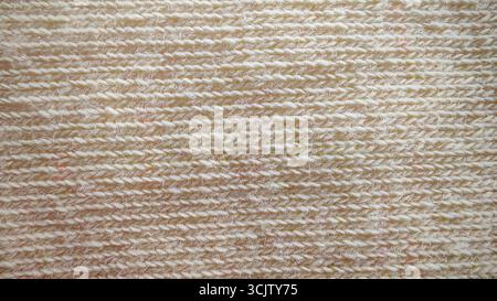 Texture macro senza cuciture di un tessuto in maglia color crema chiaro, che presenta un motivo a coste orizzontale e dettagliato di cuciture uniformi. Foto Stock