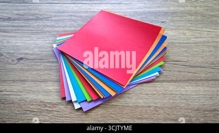 Vista dall'alto verso il basso di una pila di carta origami multicolore su uno sfondo di legno. Foto Stock