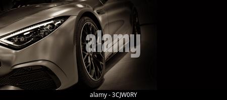Vista frontale dei fari a LED per auto sportiva su sfondo nero con tonalità seppia Foto Stock