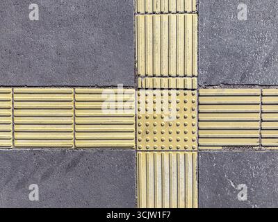 strisce gialle e bottoni sulla pavimentazione. indicatori tattili per non vedenti. Foto Stock