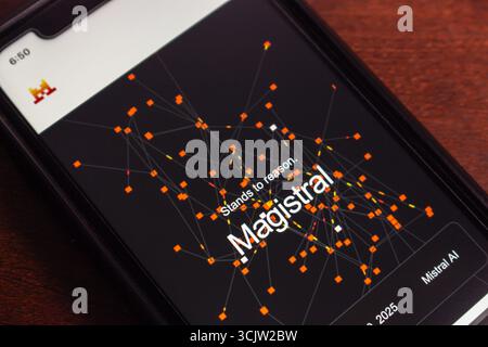 Primo piano di uno smartphone che visualizza l'interfaccia del modello Magistral ai con visualizzazione astratta della rete ed elementi di branding. Foto Stock