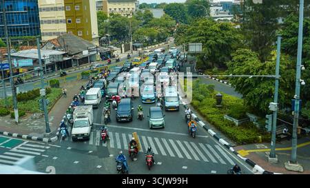 La vista aerea cattura una vivace strada della città con auto e moto che navigano in un incrocio affollato, adatto per la pianificazione urbana o il concetto di traffico vi Foto Stock