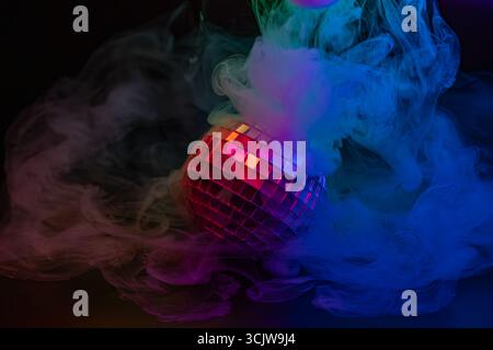Un'immagine vibrante di un ballo da discoteca che si illumina di luci arcobaleno nella nebbia, evocando un'atmosfera da festa a. Foto Stock