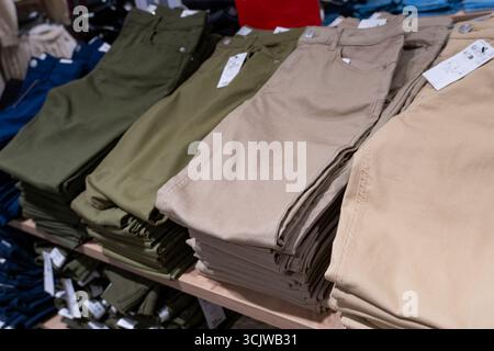 Pile di jeans blu disposte ordinatamente su scaffali di legno in un negozio di abbigliamento, che espone la moda al dettaglio e il concetto di merchandising Foto Stock