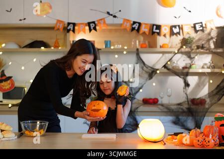 Madre e figlia si godono Halloween Pumpkin Carving insieme Foto Stock