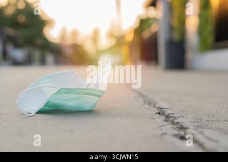 Maschera facciale monouso. Le maschere chirurgiche vengono usate con disattenzione sparse per strada. Non gettare via la maschera usata. Foto Stock