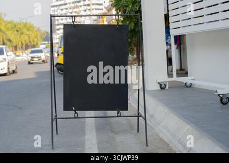 Modello di mock-up per tabellone pubblicitario nero vuoto per esterni. Cartellone stradale trasparente collocato presso un'area pranzo all'aperto di un ristorante Foto Stock