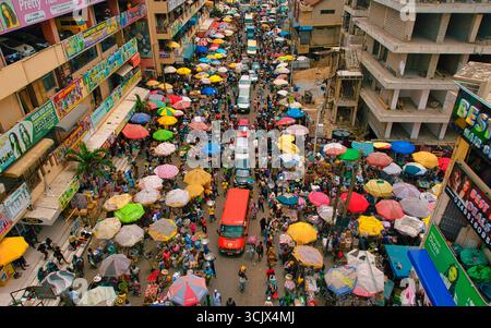 Accra, Ghana - 23 marzo 2024: Vista aerea del mercato di Makola pulsante di vita, un vivace arazzo di ombrelli colorati che ombreggiano folle e veicoli affollati in mezzo all'architettura urbana. Foto Stock