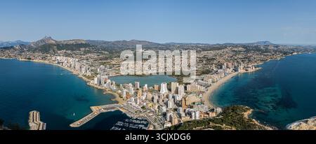 Questa immagine panoramica cattura una vista dall'alto della vivace città costiera di Calpe, in Spagna, annidata tra due splendide baie. L'iconico Peñón de Foto Stock