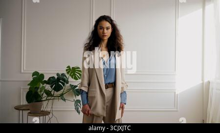 Una donna elegante elegantemente vestita in una camera luminosa circondata dal verde Foto Stock
