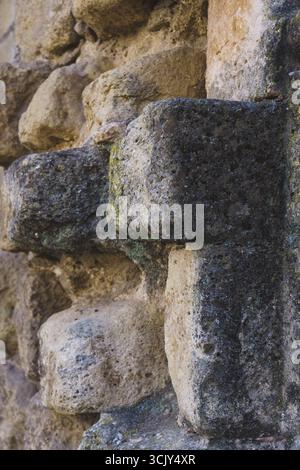 Superficie ruvida di un vecchio muro di pietra che mostra gli effetti del tempo, del tempo e della crescita del muschio a ronda, malaga, spagna Foto Stock