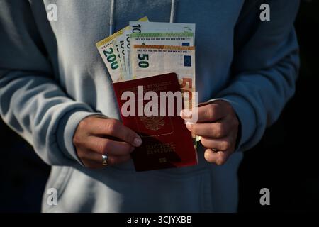 Viaggiatore in possesso di passaporto russo con banconote in euro in uscita, primo piano di 50 e 100 euro. Il concetto di trasferimento, emigrazione, o. Foto Stock