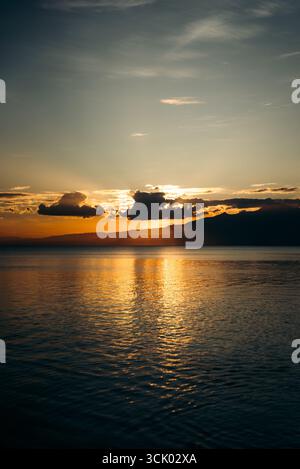 Splendido tramonto che crea una vista estetica in una combinazione di colori rosso, giallo, arancione e motivi che si affacciano sull'oceano, tranquillo e tranquillo Foto Stock