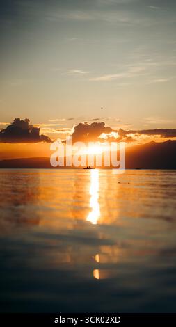 Splendido tramonto che crea una vista estetica in una combinazione di colori rosso, giallo, arancione e motivi che si affacciano sull'oceano, tranquillo e tranquillo Foto Stock
