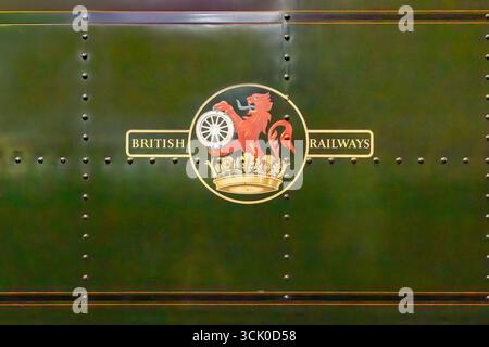 Emblema della British Railways sul lato di un treno storico, con un leone rosso su una corona che regge una ruota d'argento, scritta oro su metallo verde scuro. Foto Stock