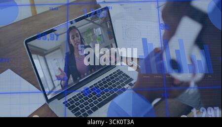 Mostra la donna che parla con un laptop in ufficio, grafici, diagrammi a griglia, due smartphone, strumenti di scrittura Foto Stock
