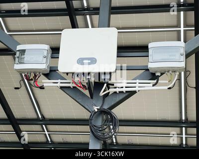 Inverter di energia solare e scatole elettriche installate sotto i pannelli solari in un ambiente esterno Foto Stock
