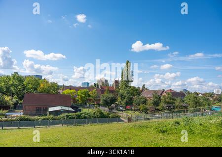 Vista su un villaggio con tetti e alberi di tegole rosse. Il cielo blu è pieno di nuvole bianche. Foto Stock