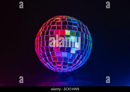 Una scintillante sfera da discoteca che riflette luci colorate, evocando un vivace ambiente da ballo Foto Stock