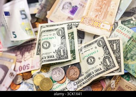 Il denaro proveniente da diversi paesi del mondo è sparso in una pila di monete e banconote. Dollari americani, lei rumena e euro. Foto Stock