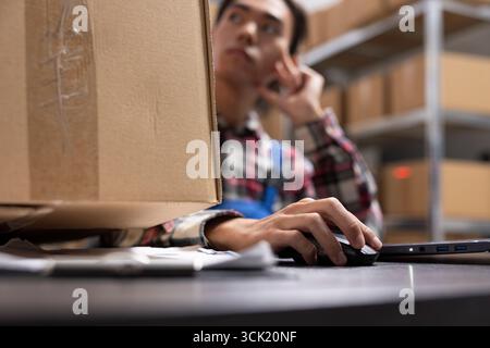 Lavoratori asiatici in un magazzino su piccola scala che gestisce merci in pacchi, attaccando etichette di spedizione alle scatole per la consegna espressa spedizione locale. Servizio di distribuzione per piccole imprese. Primo piano. Foto Stock