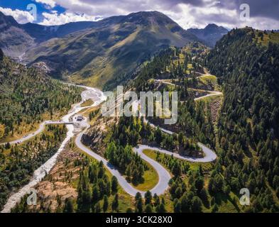 Giro in droni ad alto angolo della strada del ghiacciaio Kaunertal in Austria che si snoda attraverso una valle lussureggiante. Una strada drammatica a serpentina si snoda attraverso le foreste alpine. Foto Stock