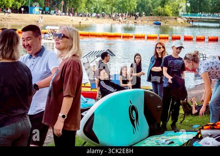 La gente prepara una barca per il surf SUP sul lago in estate: Abakan, Russia - 8 giugno 2024 Foto Stock