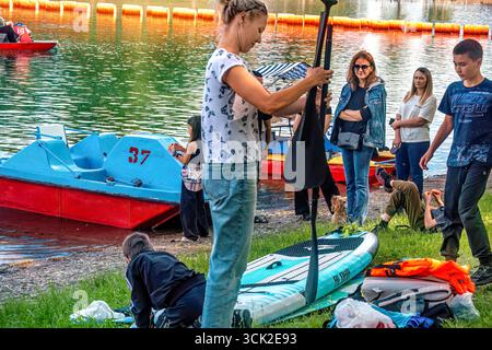 La gente prepara una barca per il surf SUP sul lago in estate: Abakan, Russia - 8 giugno 2024 Foto Stock