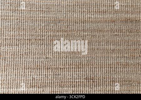 Primo piano del tappeto in fibra naturale intrecciata sullo sfondo. Tappeto ecologico realizzato a mano per interni, decorazioni e design. Foto Stock