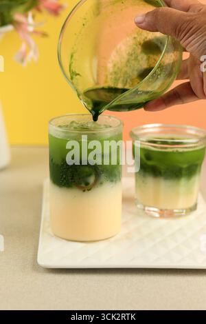 Versare il Matcha nel processo di produzione del latte per preparare il Matcha latte, bevanda virale giapponese Foto Stock
