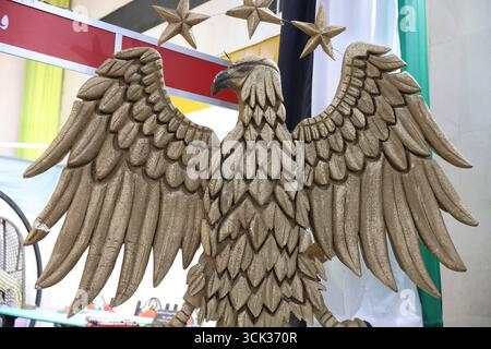 Aquila con emblema nazionale siriano esposta all'interno del padiglione della Fiera Internazionale di Damasco. Una grande scultura dell'aquila simbolo nazionale siriana è esposta all'interno di un padiglione presso la Fiera Internazionale di Damasco dopo la caduta del dominio degli Assad. I visitatori si fermeranno per scattare foto accanto all'aquila color abbronzatura, le cui ali rappresentano i 14 governatorati siriani e le piume di coda simboleggiano le cinque regioni principali del paese. Adottato ufficialmente il 3 luglio 2025, l'emblema è diventato un marcatore della nuova identità visiva di Syrias. Damasco Siria Copyright: XMohammadxBashirxAldaherx Foto Stock