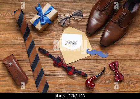 Accessori da uomo e busta con testo BUONA GIORNATA DEL PAPÀ su sfondo in legno. Vista dall'alto Foto Stock