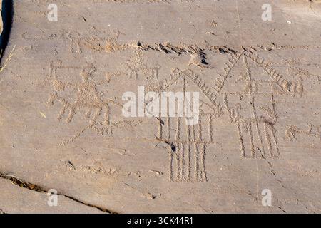 Valcamonica, Italia - 11 gennaio 2025: Vista di antiche incisioni rupestri incise sulla superficie in pietra, raffiguranti figure e motivi geometrici sotto la luce soffusa. Foto Stock