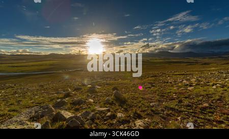 Vista del sole che splende sulle verdi praterie con un piccolo fiume che scorre, sotto un cielo blu con soffici nuvole, Skardu, Gilgit Baltistan, Pakistan. Foto Stock