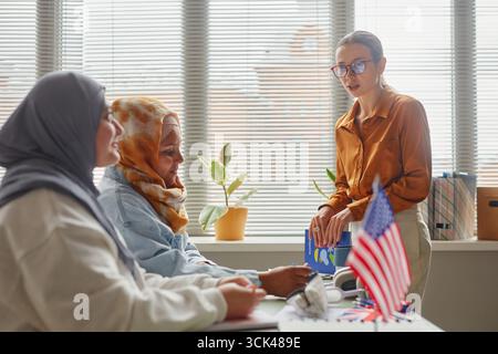 Giovane donna caucasica che insegna diversi studenti adulti durante la lezione di lingua Foto Stock