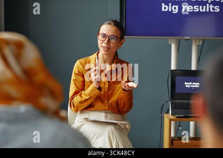 Giovane donna adulta caucasica che spiega i concetti linguistici durante la lezione scolastica Foto Stock