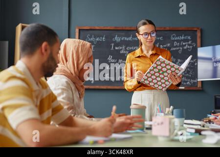 Giovane donna caucasica che insegna adulti multietnici durante la lezione della scuola di lingue Foto Stock