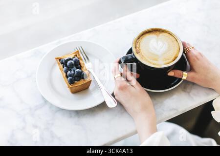Cappuccino con motivo a base di schiuma di latte nelle mani delle donne Foto Stock