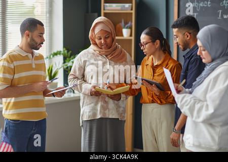 Diversi giovani adulti che collaborano durante l'attività scolastica Foto Stock