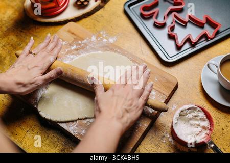 La donna srotola l'impasto per i biscotti di Natale Foto Stock