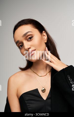 Una giovane donna indossa elegantemente un corsetto nero alla moda, trasudando fascino. Foto Stock