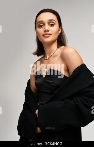 Una giovane donna indossa con eleganza un elegante abito nero con corsetto. Foto Stock