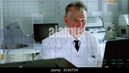 Scienziato senior che indossa un camice da laboratorio e una cravatta che analizza i dati in tempo reale sui monitor in laboratorio, con lavello Foto Stock