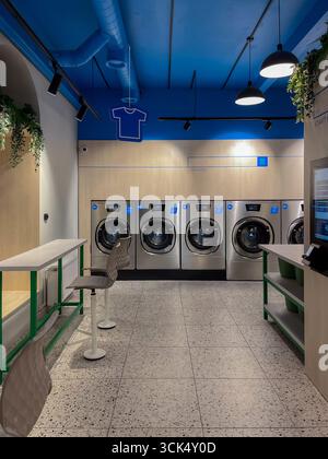 Riga, Lettonia - 4 settembre 2025: Moderna lavanderia con lavatrici Speed Queen, aree self-service e un'estetica pulita e moderna con vi Foto Stock