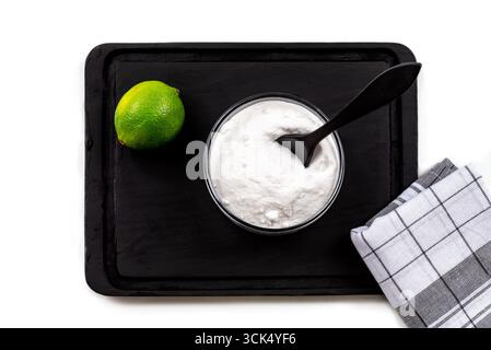 Bicarbonato di soda in una piccola ciotola di vetro accanto a un lime e un telo da tè Foto Stock