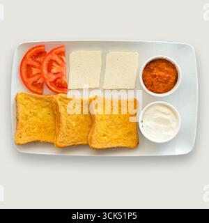 Un piatto per la colazione con pane tostato, pomodori, formaggio e salse. Foto Stock