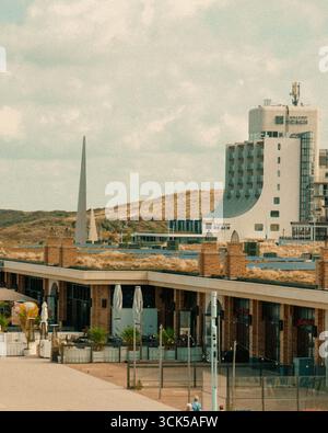 L'hotel fronte spiaggia dune dall'architettura moderna e paesaggio costiero caratterizzato da Carlton Beach hotel, colline sabbiose, edifici a lungomare e area di svago all'aperto Foto Stock