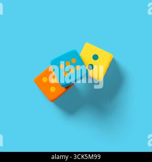Tre dadi colorati in arancione, blu e giallo, con diversi schemi di punti, ideali per giochi e attività ricreative. Foto Stock